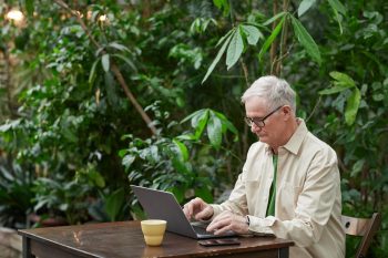 older man at outside table working on computer; Do Entrepreneurs Ever Really Retire?