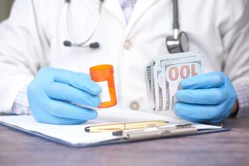 doctor with prescription in one hand and money in the other