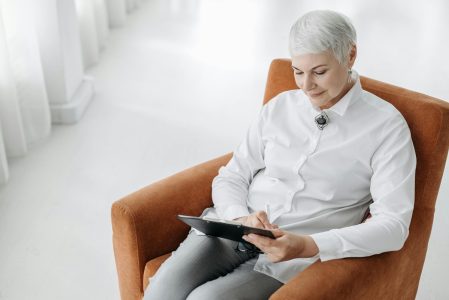 woman sitting in chair with ipad; Don't Outlive Your Money Fintech is Bridging Gap
