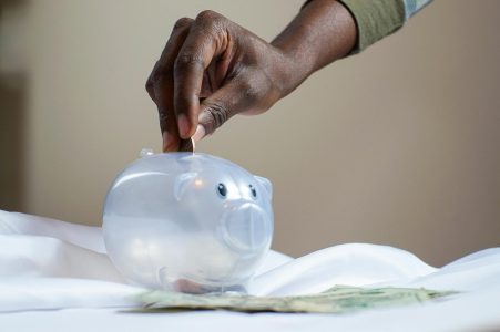 person putting money in a white piggybank; Turbocharge Your Retirement Savings