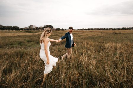 younger couple running through grass; How to Reverse-Engineer Your Retirement Date Starting Today