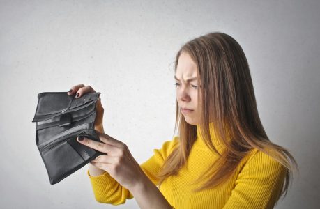 woman looking on in dismay at an empty wallet; Psychology of Overspending