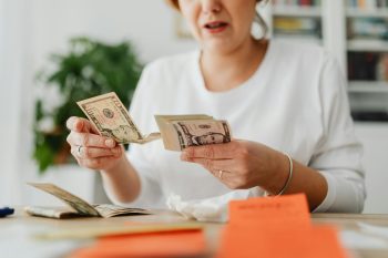 woman with money in hand; Why a High Salary Doesn’t Mean You’re Rich