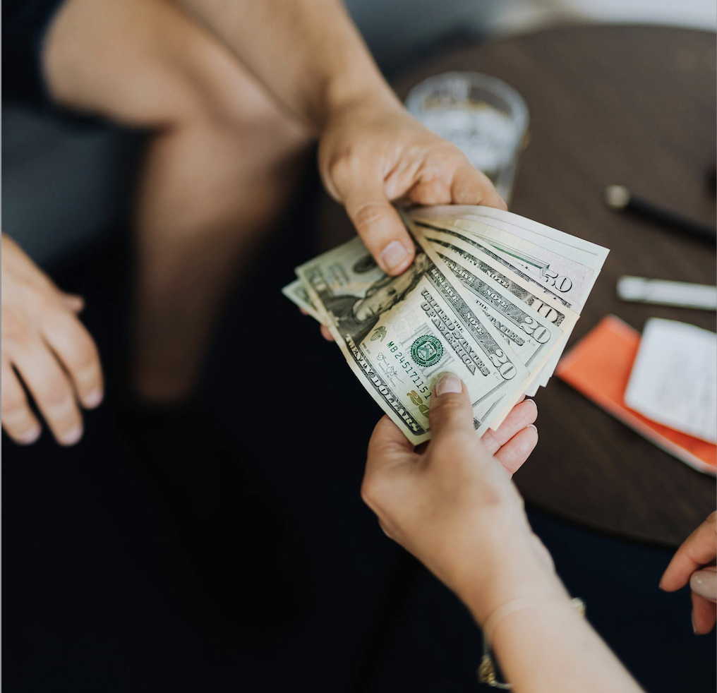 one person handing money to another; Americans Borrow to Protect Their Retirement Accounts