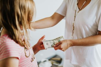 mother handing child cash; How Your Financial Choices Shape the World
