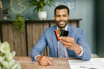 man at desk looking at his credit cards; Using Credit Cards for Cash Flow