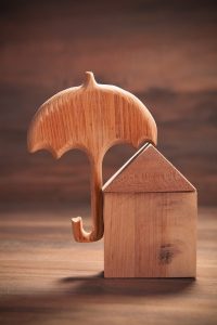 Wooden umbrella protecting a wooden house on a wooden surface.