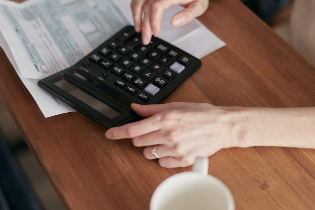 Person reviewing tax documents and using calculator; Addressing Challenges Independent Workers