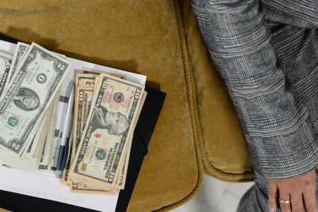 Money laying on couch beside person who is doing financial planning; Annuity Payments Financial Goals
