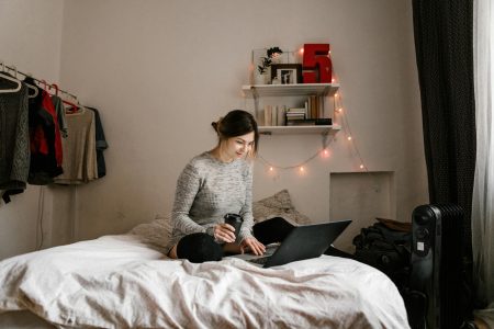 woman sitting on her dorm room bed; Lucrative Business Ideas for College Students