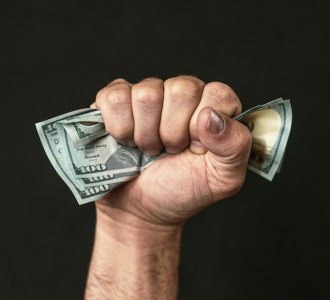 man with money in fist; Make $5,000 a Month in Dividend Income