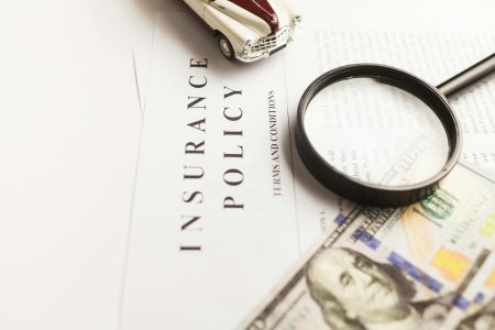 a magnifying glass on an insurance document; Why This High-Yield Life Insurance Is a Scam