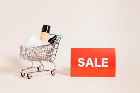 a shopping cart next to a red sale sign; Bundling Protecting Margins While Offering Deals