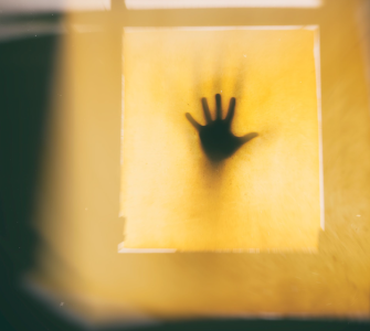 a mysterious shadowed hand up to a lit window; Fear Sabotages Financial Growth
