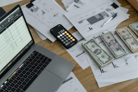 person figuring out their money on a desk; Money Habits Separate the Wealthy From Everyone Else