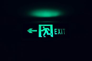 graphic with an exit sign in green on a black background; Retirement Planning Lessons From Founders Who Exited Early
