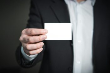 person holding their business card out to someone else; Build Wealth Without Tying Your Identity to Your Business