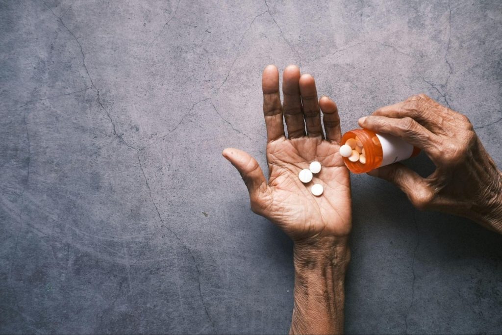 Close-up of elderly person's hands holding daily prescription medication; Changing Care Needs