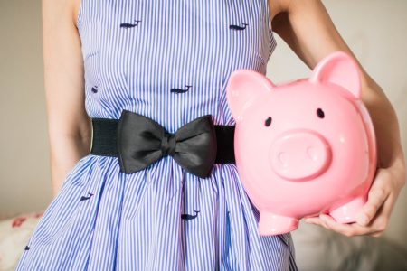 woman holding a pink piggy bank; How Much Should You Have in an Emergency Fund?
