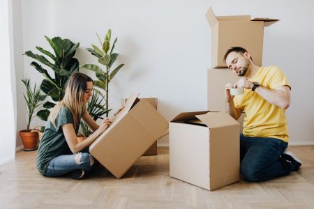 Couple packing boxes on the floor in their home; family move budget
