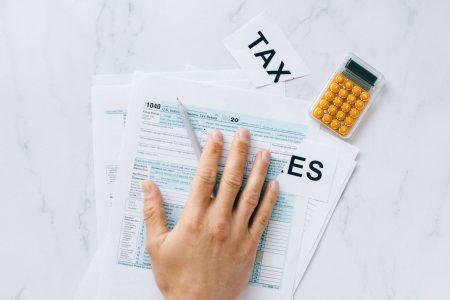 person with hand over the taxes they are working on; Business Expenses Can You Actually Write Off