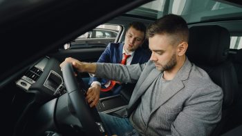 man looking at a new car with a sales guy; Buy Now, Pay Later risks