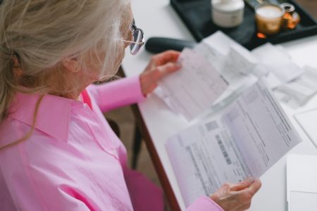 senior woman using checks to write out her bills; Checks Why Paper Payments Are Finally Dying