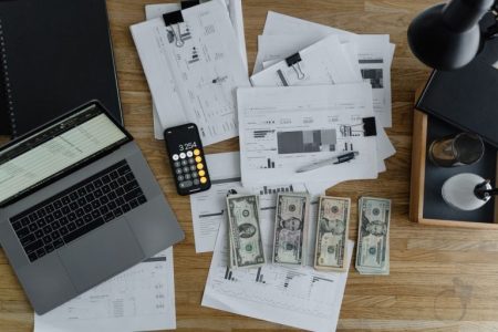 money and documents on a desk by computer;