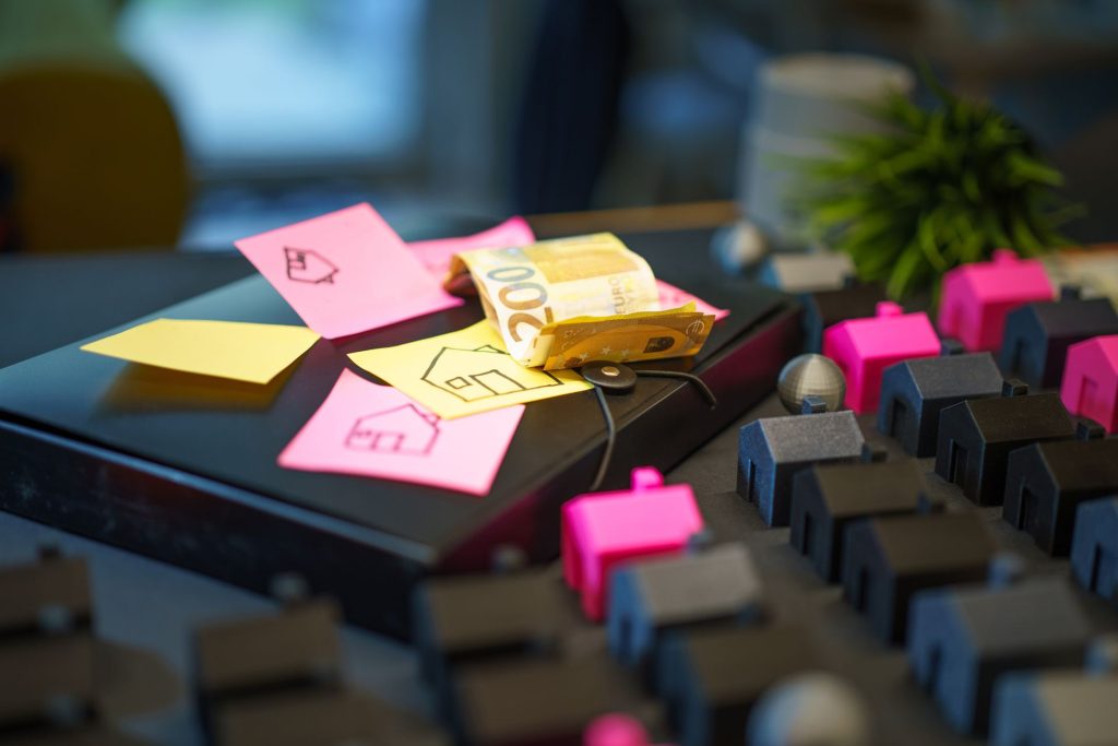black keyboard with pink houses inserted and sticky notes on the side; Should You Pay Off Your Mortgage Early or Invest