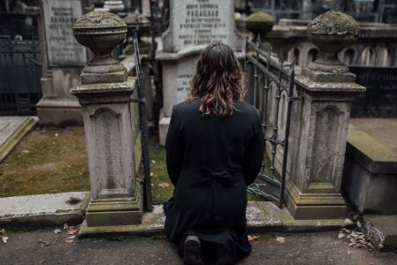 black and gray photo woman in front of a memorial; What Happens to Your Debt When You Die?