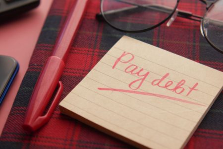 pay debt written on a sticky note