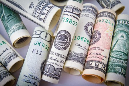 Rolled United States banknotes of various denominations arranged together