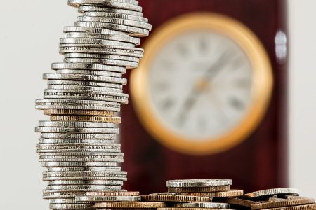 a stack of coins with a clock in the background; Compound Interest Why Is It So Powerful?