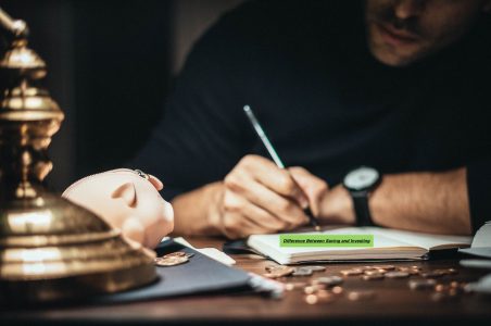 a person writing in their journal about their finances --to save or invest;
