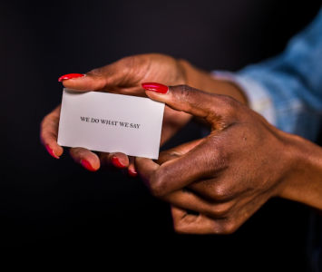 a woman holding a card saying we do what we say; How Much Should You Have Saved for Retirement by Age?