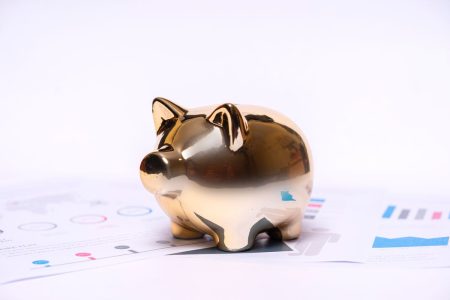 Gold piggy bank sitting on top of retirement savings documents; How Much To Retire