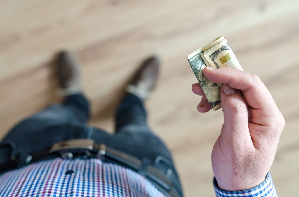 man holding a small amount ot cash to invest; Start Investing With Little Money in 2026