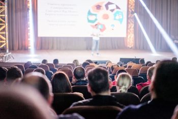 a person on stage speaking at a conference;