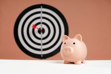 a target with an arrow in center and a pink piggybank;