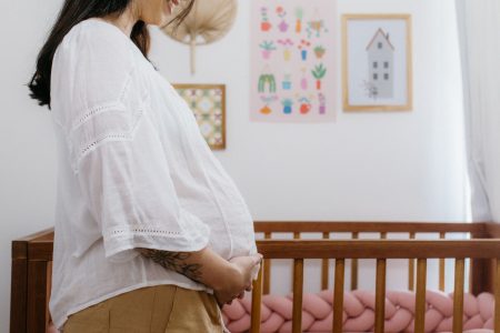 profile of a pregnant woman in front of baby room